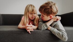 Kaksi lasta makaa sohvalla ja katsoo toisiaan kireän oloisina